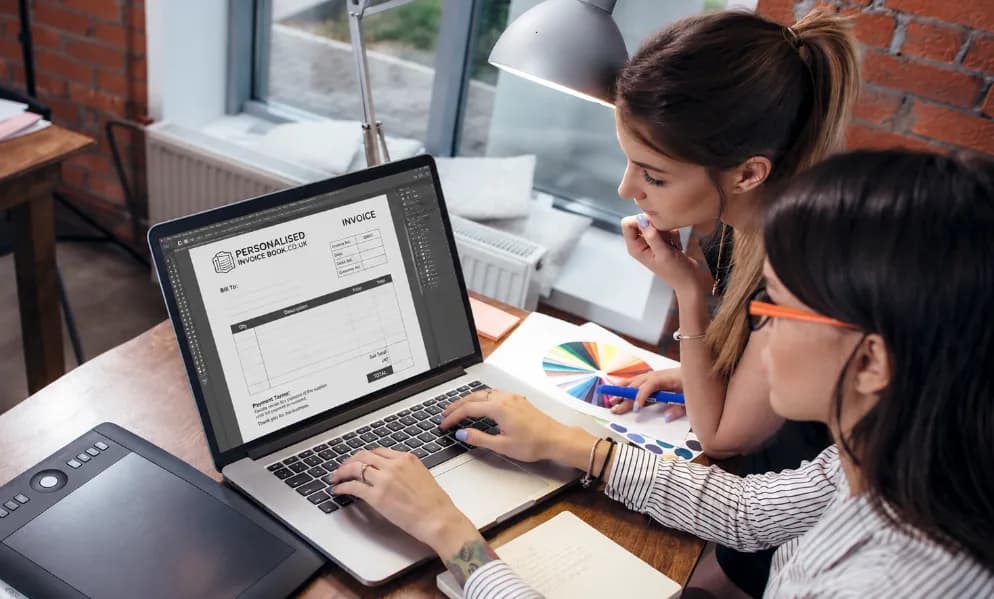 Two designers setting an invoice book design on screen